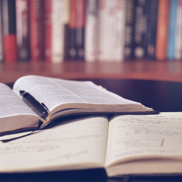 books open on a table with stacks of books in background