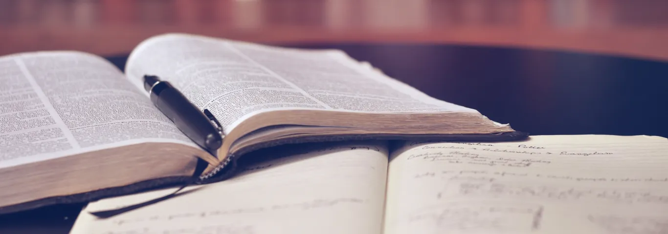 books open on a table with stacks of books in background