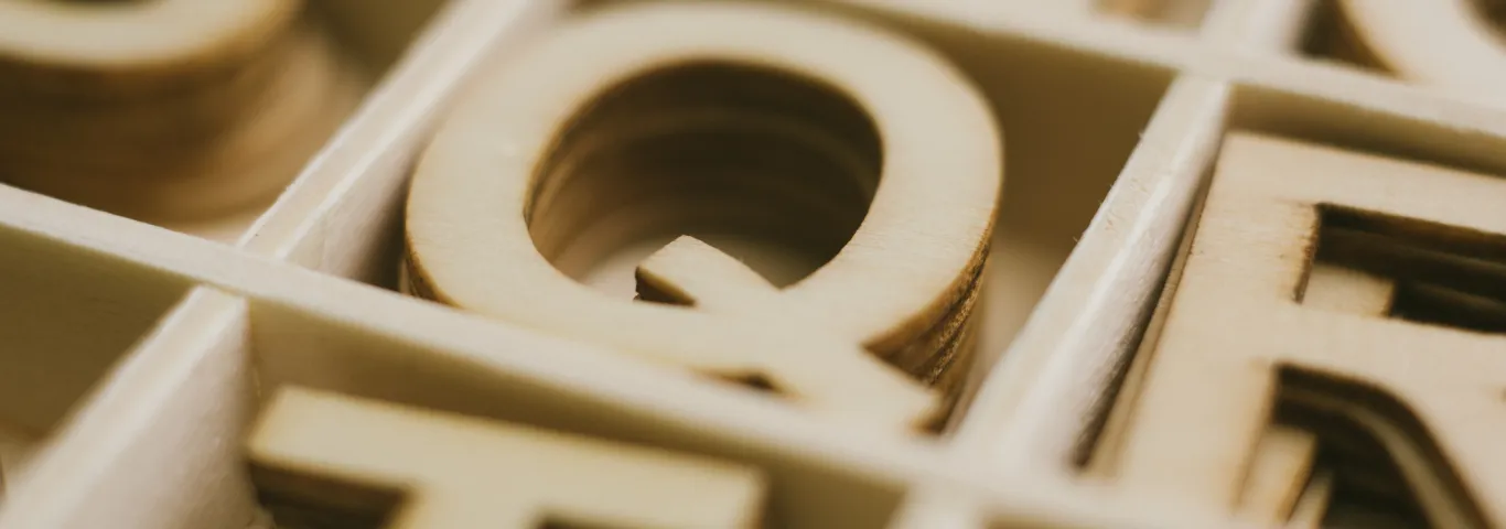 wooden letters in boxes. Letter Q is in focus