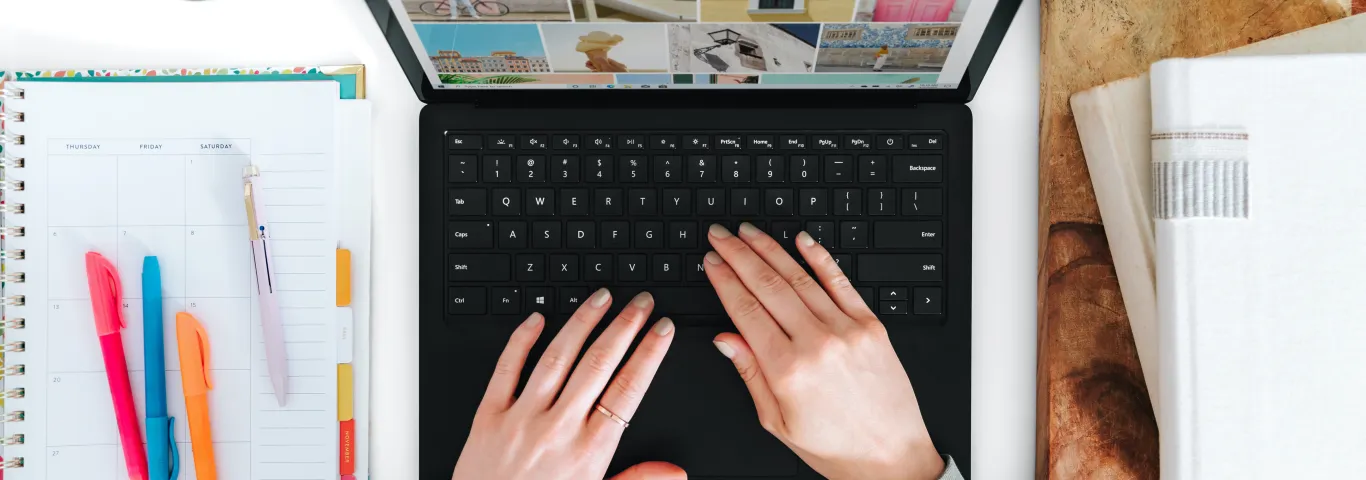 individual typing on a computer with a notebook and highlighters to their left