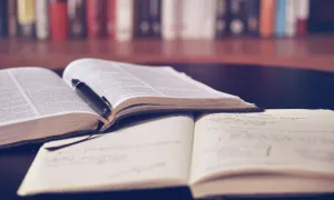 books open on a table with stacks of books in background