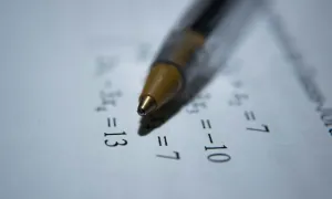 pen resting on a paper with math equations written on it