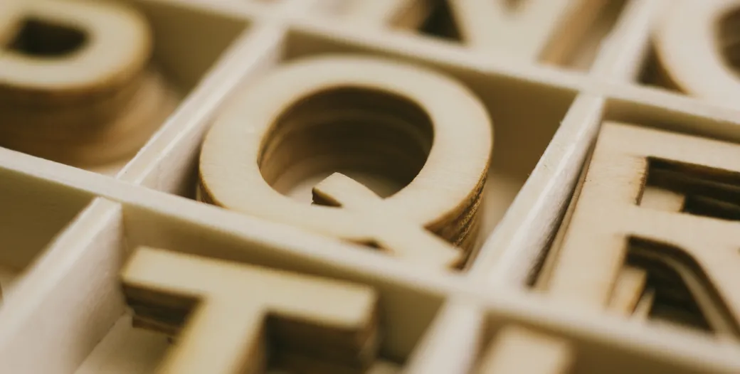 wooden letters in boxes. Letter Q is in focus