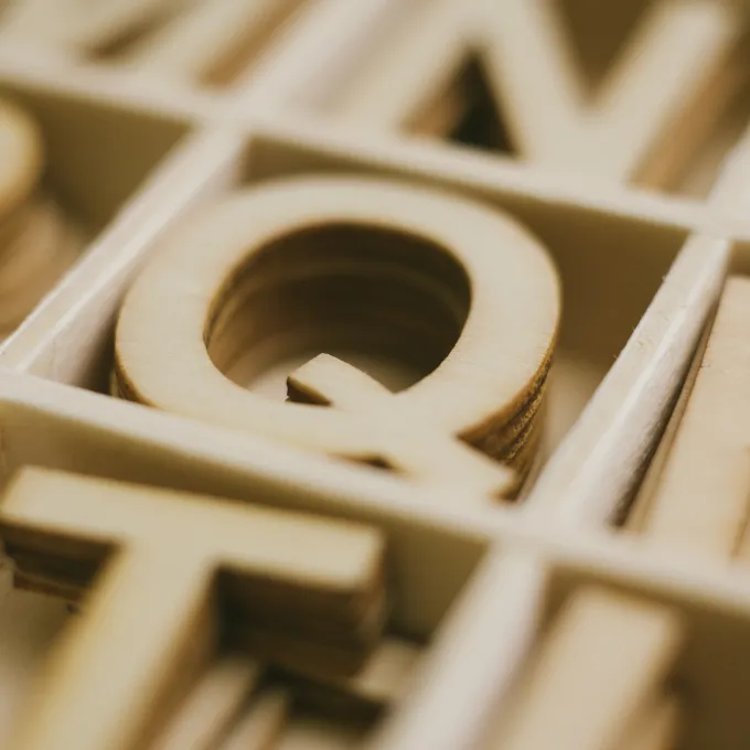 wooden letters in boxes. Letter Q is in focus